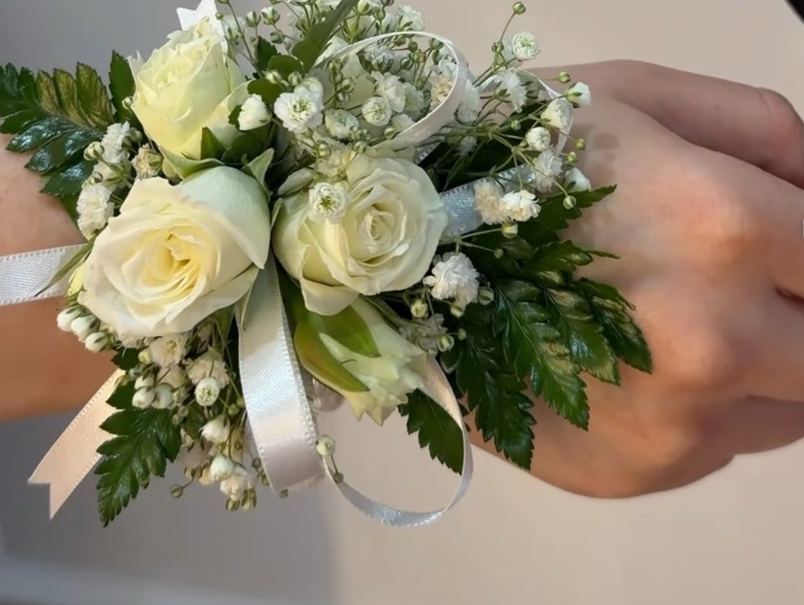White rose wrist corsage with baby's breath, greenery, and satin ribbon